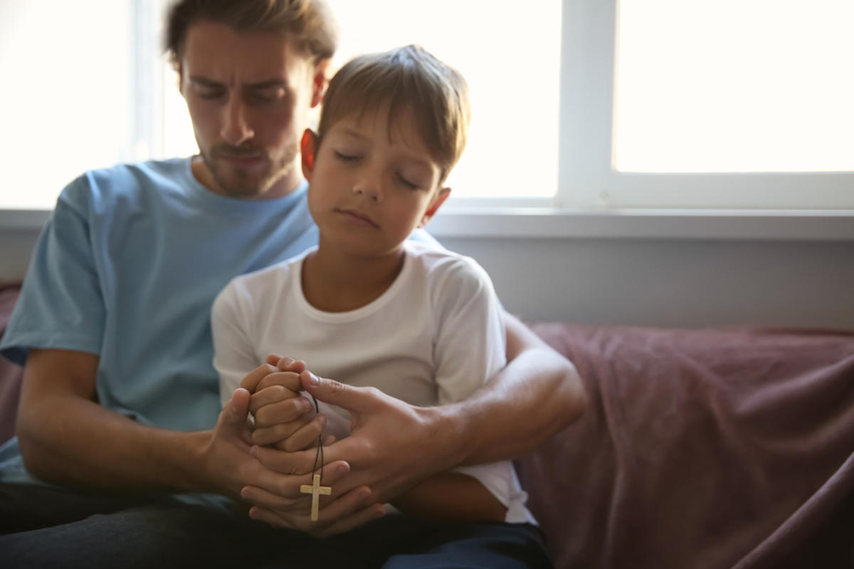 Pai e filho rezando o terço