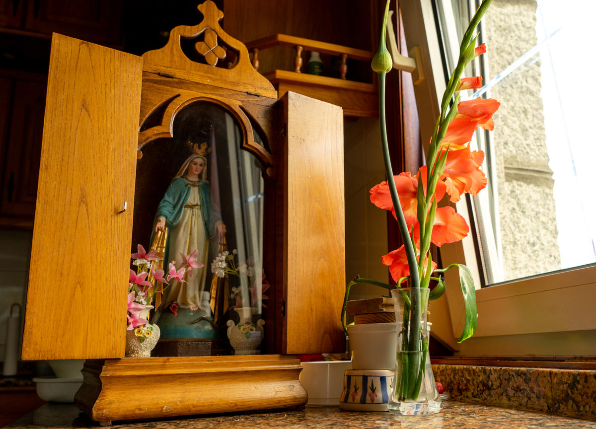 imagen de una virgen colocada en un altar de madera con una tapa para llevar de una casa a otra
