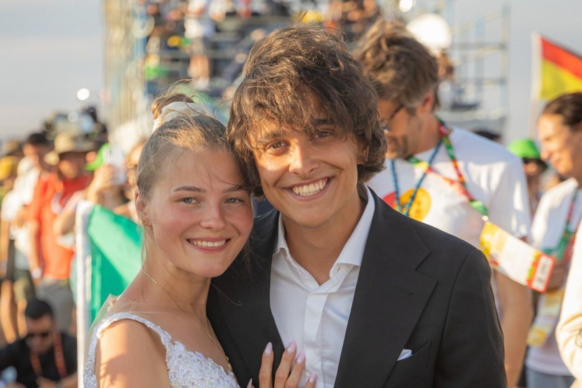 A Polish couple wearing a wedding dress and a suit smile at the camera at World Youth Day 2023 in Lisbon