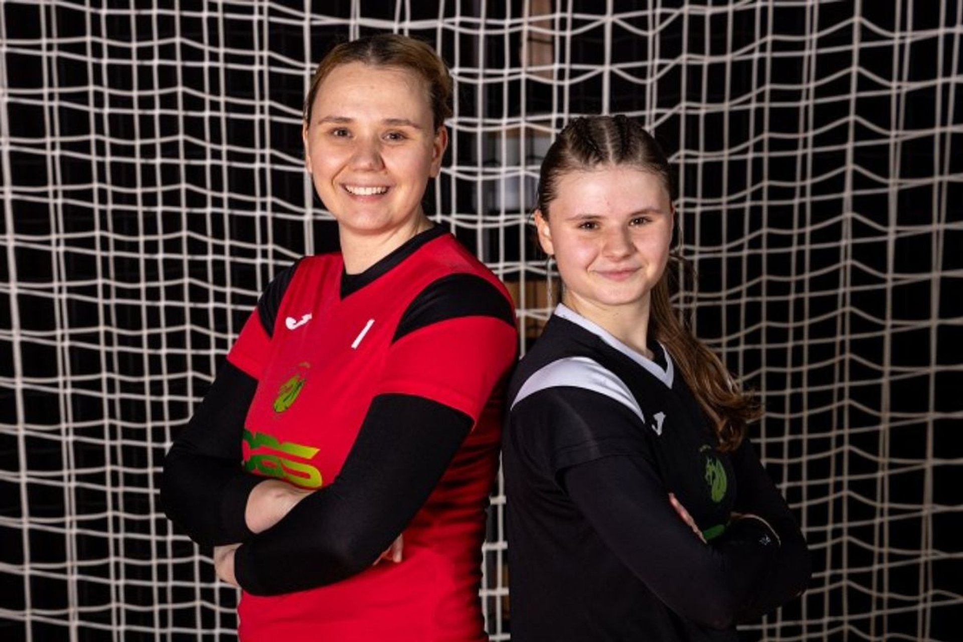 Mother and daughter stand in front of a handball goal net