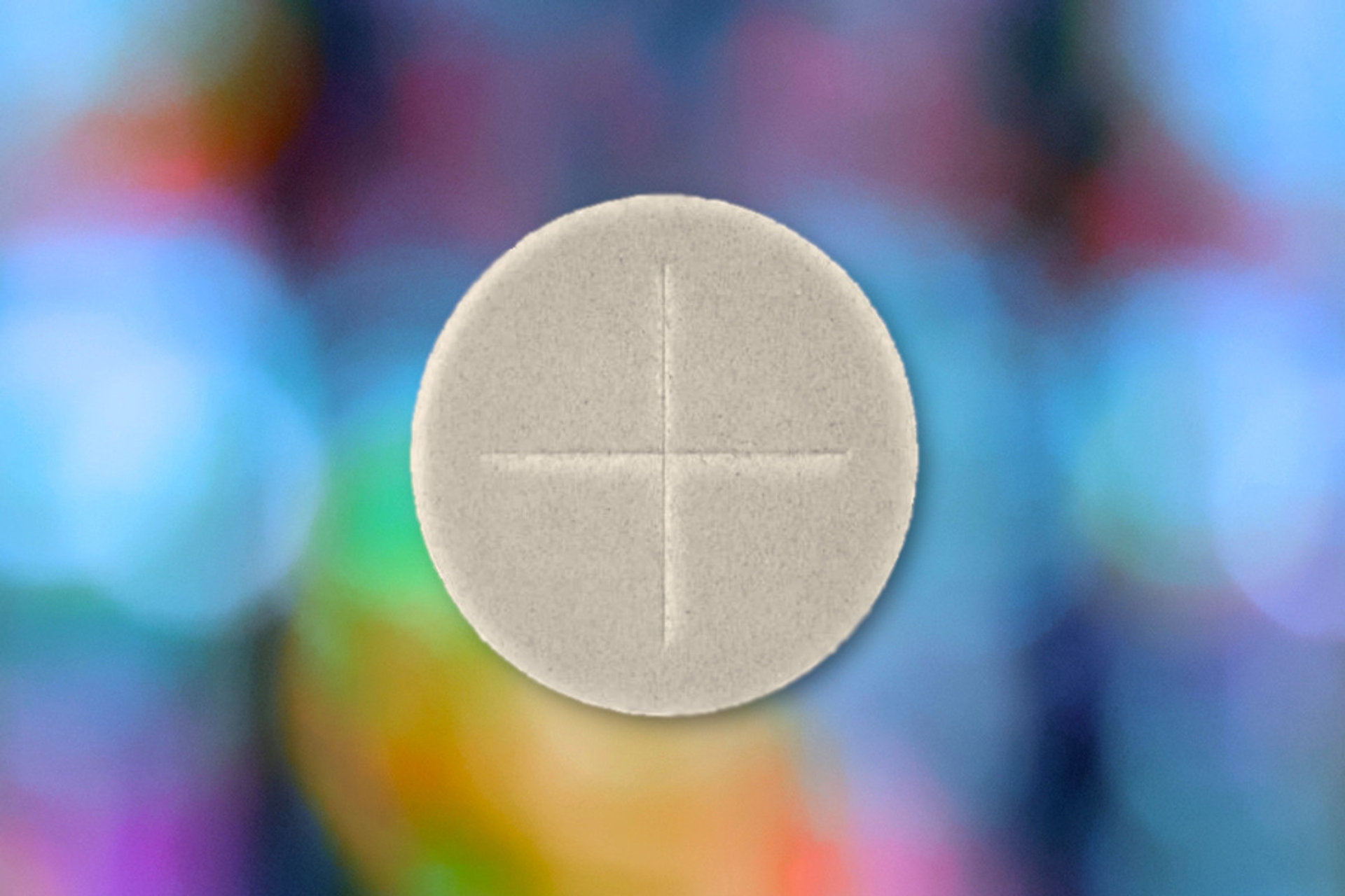 Holy communion host against blurred stained glass window