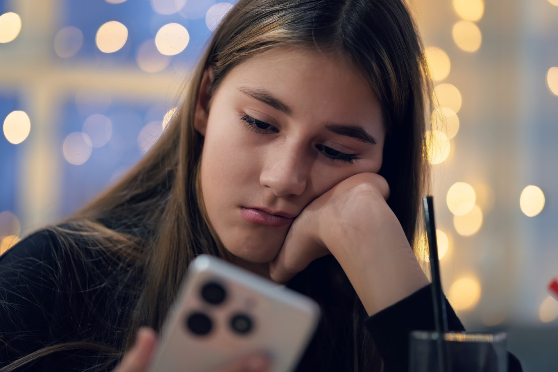 A teenage girl holds a smartphone in her hands