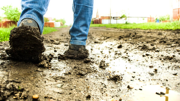 Ubłocone buty na drodze pokrytej błotem