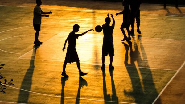 Boys playing basketball at dusk
