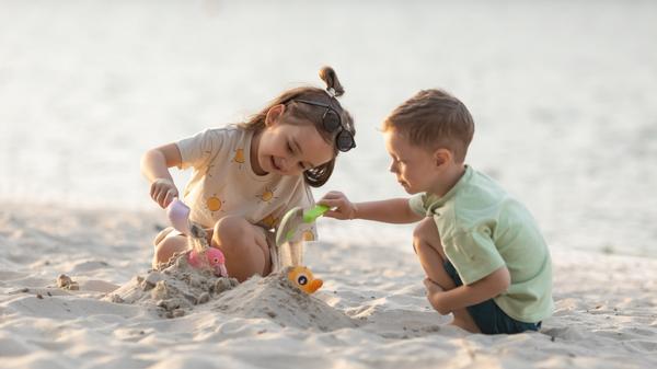 Children boy and girl playing on the beach on summer holidays