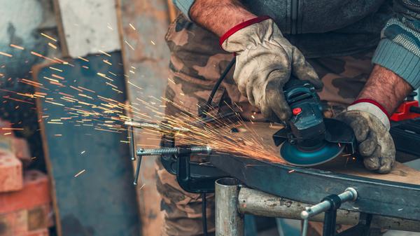 Primer plano de la trituradora de trabajo manual con chispas intensas, destacando el esfuerzo físico y la dedicación. Concepto de trabajo duro, estilo de vida de cuello azul, resistencia y trabajo diario.