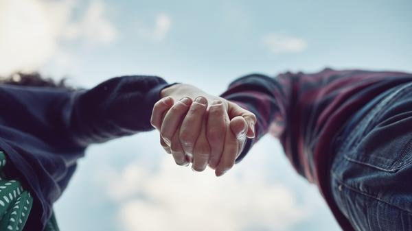 Low angle, blue sky and couple with love, holding hands and romance with adventure