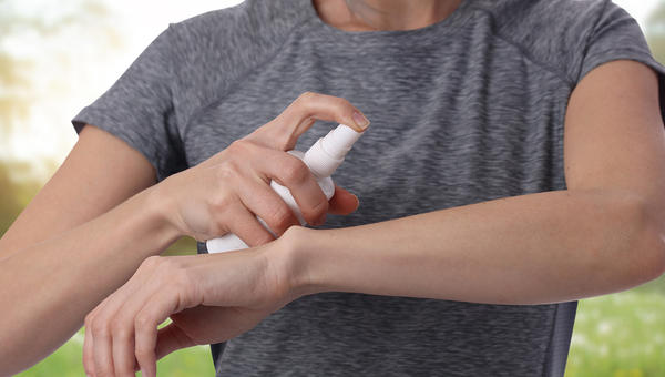 FEMME METTANT DU SPRAY ANTI MOUSTIQUE