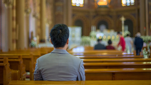 ASIAN MAN PRAYING IN CHURCH