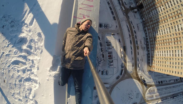 man selfie on edge of roof of tall building