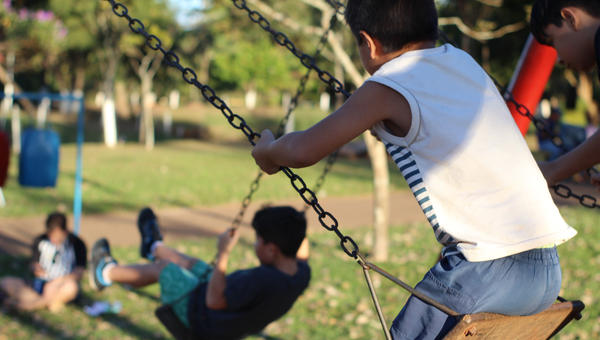 children playing in the park playground on a sunny and green day