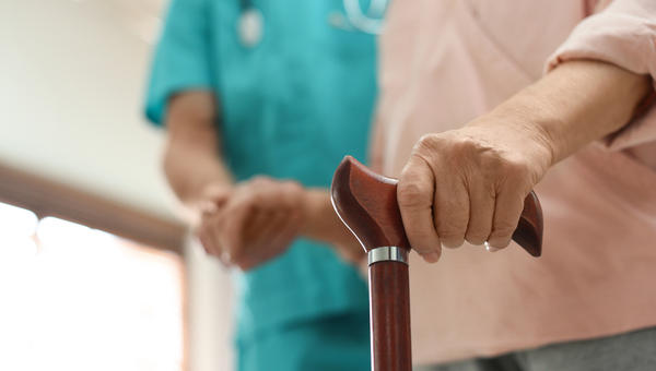 Pacjentka w hospicjum porusza się o lasce, podtrzymywana przez lekarza