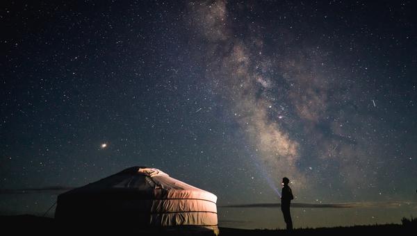 Człowiek patrzy na usiane gwiazdami nocne niebo