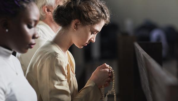 Jovens rezando o terço em igreja