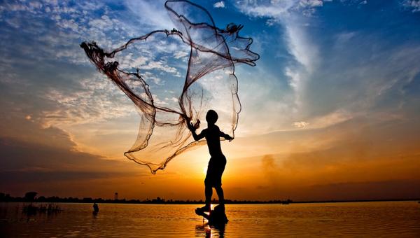 throwing fishing net during sunset , thai