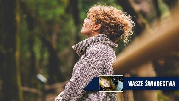 Kobieta w średnim wieku zatrzymała się podczas spaceru w lesie i spogląda w górę ze spokojem