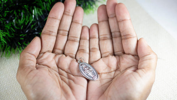 Girl-Hands-Holding-Miraculous-Medal-and-Praying-to-Our-Lady-Holy-Mary-Mother-of-God-shutterstock_1574