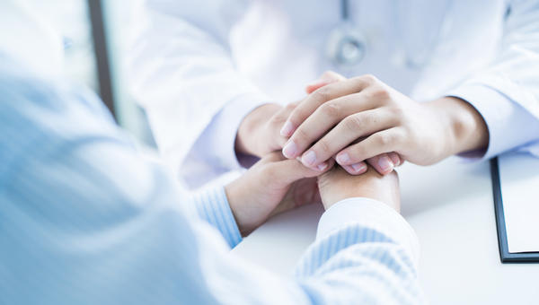 Médico segura as mãos de um paciente