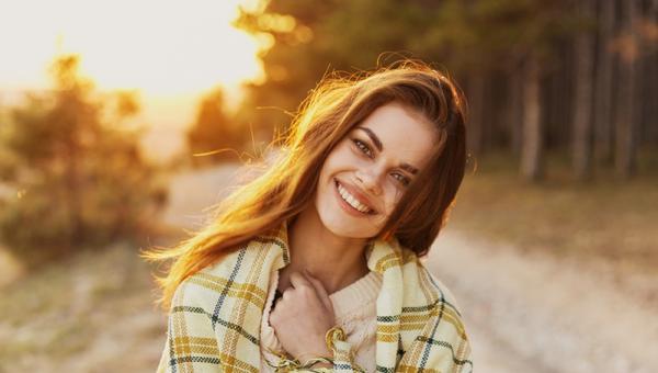 Happy woman with bread on her shoulders laughs front view and sunset in the background