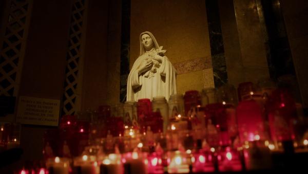 Estátua de Santa Teresinha cercada de velas