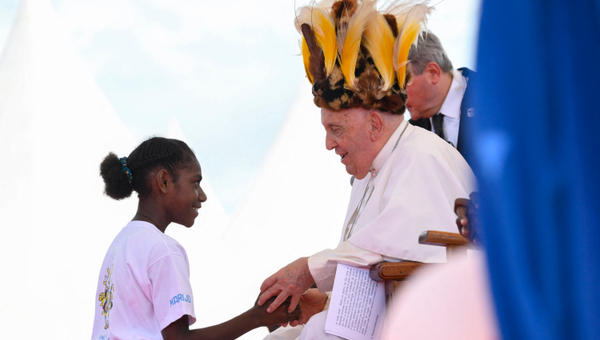 Pope Francis, seen wearing a traditional headdress, interacting with a youth during a meeting with Catholic faithful of the diocese of Vanimo in front of Holy Cross Cathedral in Vanimo, Papua New Guinea, on September 8, 2024