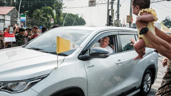A man holds his baby for Pope Francis to bless as he leaves for Jakarta's Soekarno-Hatta International Airport ahead of his departure to Papua New Guinea's capital Port Moresby on September 6, 2024.