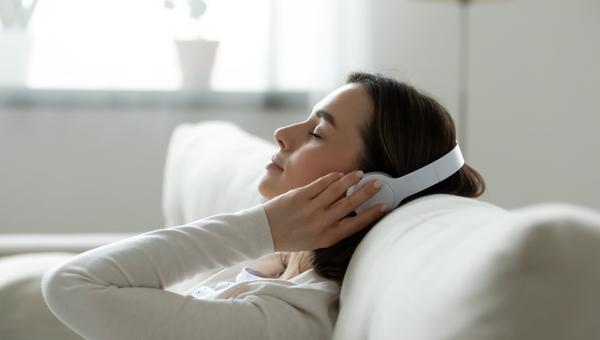 Calm female resting leaned on comfy couch in living room spend free time at home closed eyes enjoy music listening