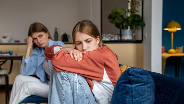 Frustrated teenage girl sits hugging his knees, looks away