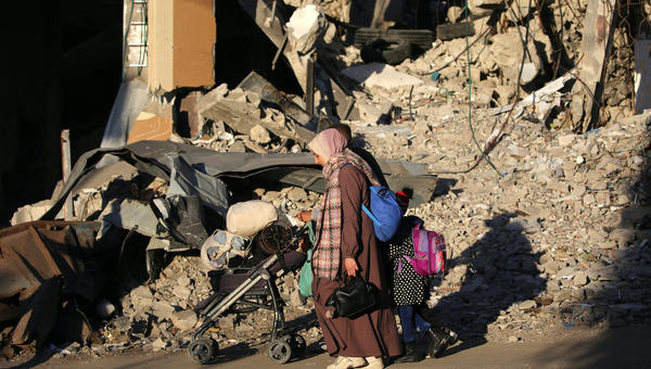 Mother and child walk past rubble in Gaza Strip