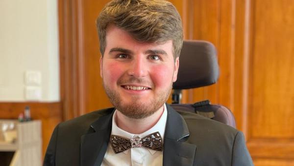 Portrait of Nicolas Rengade, ruddy-faced and smiling, dressed up and sitting in a wheelchair