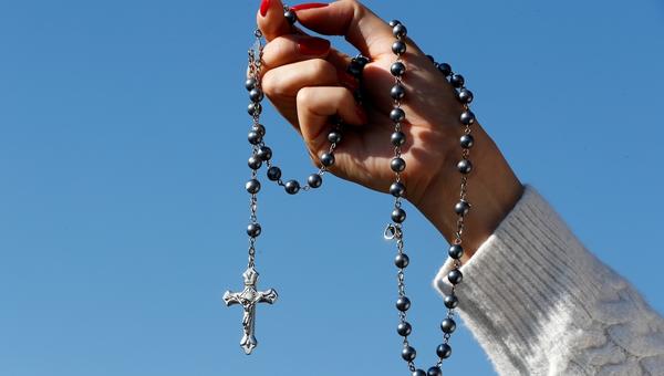 woman-hand-rosary-blue-sky