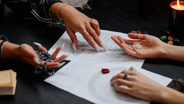 Close up of fortune teller pointing at astrology chart during spiritual seance with young woman