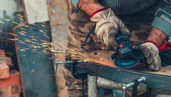 Primer plano de la trituradora de trabajo manual con chispas intensas, destacando el esfuerzo físico y la dedicación. Concepto de trabajo duro, estilo de vida de cuello azul, resistencia y trabajo diario.