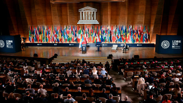Pope Leo XIV delivers a speech on stage, next to UNESCO Director-General Khaled El-Enany (R), during a visit at the UNESCO