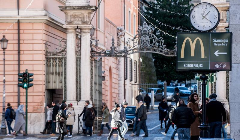 January 5 2017 : A sign showing the direction of a McDonald restaurant is seen near an entrance of the Vatican in the background.