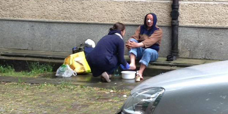 Kobieta myje nogi bezdomnemu na ulicy