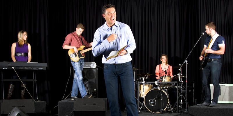 MAN WITH BIBLE PREACHING ON STAGE