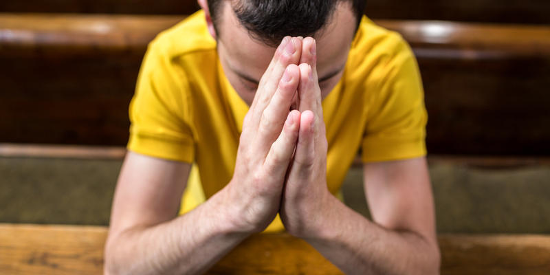 MAN PRAYING IN CHURCH PEW