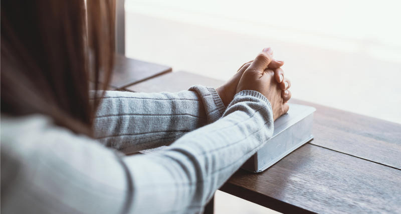 JEUNE FEMME PRIANT AVEC SA BIBLE