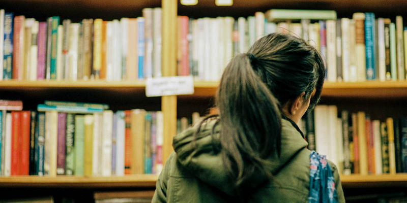 WOMAN LOOKING AT BOOKSHELF