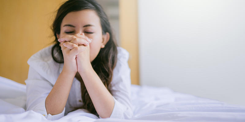 WOMAN PRAYING ON THE BED