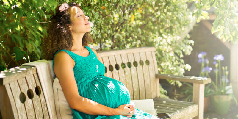 PREGNANT WOMAN SITTING IN PARK