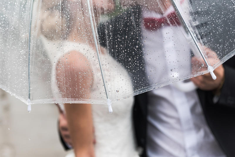 BRIDE AND GROOM UNDER UMBRELLA