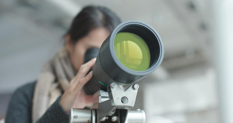 WOMAN LOOKING THROUGH TELESCOPE