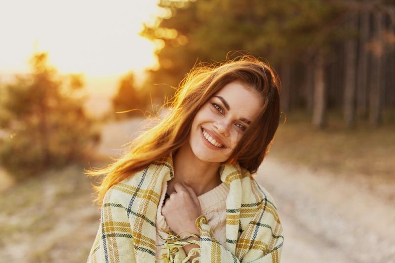 Happy woman with bread on her shoulders laughs front view and sunset in the background